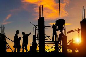 silhouette de ingénieur et ouvrier équipe vérification projet à bâtiment site arrière-plan, construction site avec le coucher du soleil dans soir temps Contexte photo