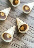 croustillant gaufre tasses avec Chocolat et noisettes sur le en bois planche photo