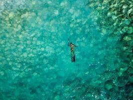 aérien drone vue de une la personne Faire chasse sous-marine sur cristal bleu l'eau. récréatif pêche et été activité. heure d'été. photo
