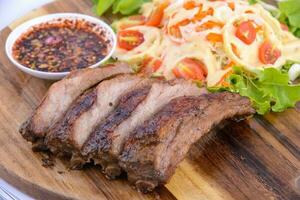 steak de porc rôti sur la plaque de bois avec sauce thaï. photo