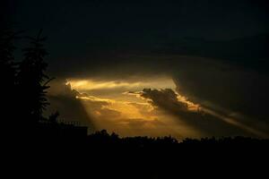 foncé dense ciel et des rayons de chaud Orange lumière avoir en dehors de le des nuages photo