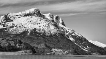 fjord avec neige couvert Montagne sur horizon dans noir blanche. le l'eau dans Norvège photo