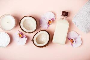 noix de coco pétrole et moitiés de Frais noix de coco sur une rose Contexte. cheveux se soucier spa concept photo