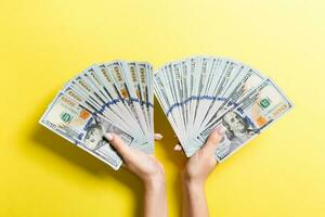 ventilateur de un cent dollar factures dans femelle mains sur coloré Contexte. investissement concept photo