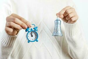 une fille tenant une montre et une cloche. le nouvel an ou noël arrive. concept du nouvel an photo