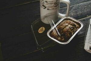 banane gâteau sur une noir en bois table avec Remarque livre, lunettes, et café tasses. photo