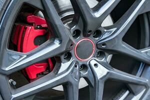 rouge frein étrier roues de une puissant voiture, frein disque. photo