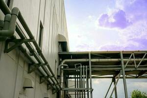 fermer échappement et air Conditionneur conduits dans le tuyau pont pour soutien usine bâtiment sur bleu ciel avec des nuages et Soleil éclater Contexte. photo