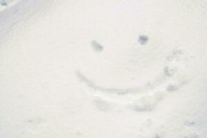 smiley visage dessin sur neige dans hiver saison. photo