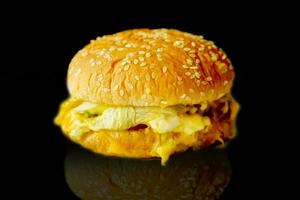 fermer poisson Burger avec fromage isoler sur noir Contexte et refection ombre. photo