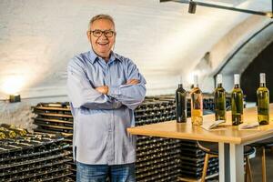 portrait de Sénior homme qui possède vignoble. il est examiner qualité dans le sien du vin cave. industrie du vin fabrication concept. photo