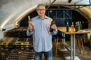 portrait de Sénior homme qui possède vignoble. il est examiner qualité dans le sien du vin cave. industrie du vin fabrication concept. photo