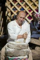 une vacances de vieux artisanat. une homme broie farine dans le vieux manière avec le Aidez-moi de pierre meules. photo