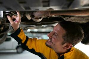 auto réparation mécanicien le châssis de le voiture est étant inspecté pour dommage causé par lourd collisions. photo