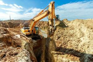 deux excavatrice sont creusement sol dans le construction site sur ciel arrière-plan, avec blanc duveteux nuage photo