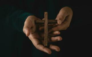 spiritualité, religion et espérer concept. la personne avec en bois traverser sur mains. symbole de humilité, supplication, croyez et Foi pour Christian personnes. foncé Ton. tondu et sélectif concentrer photo