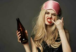 en colère femme avec une bouteille de Bière dans sa main avec brillant maquillage et une rose sommeil masque photo