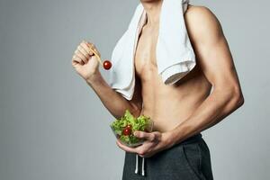 sportif homme dans une serviette sur le sien épaules une assiette de salade en bonne santé nourriture une pompé en haut torse photo