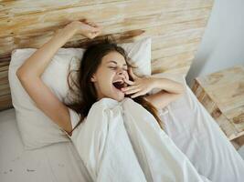 femme mensonge dans lit veille en haut après sommeil bâillement bien Matin photo