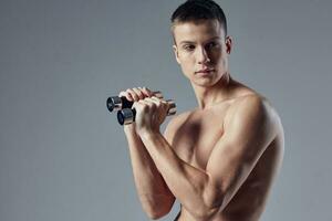 sportif homme avec pompé corps avec haltères dans mains faire des exercices aptitude tondu vue photo