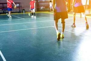 une badminton athlète enveloppements le sien droite le genou avec une blanc le genou bandage à soutien le sien le genou et guérir le sien blessure tandis que en jouant badminton ensemble avec le sien copains dans le badminton rechercher. photo