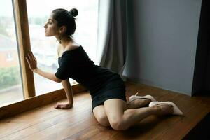 brunette dans une noir robe près le fenêtre posant élégant style photo