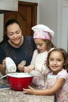 mère et filles ayant amusement dans le cuisine cuisson ensemble. en train de préparer petits gâteaux avec maman photo