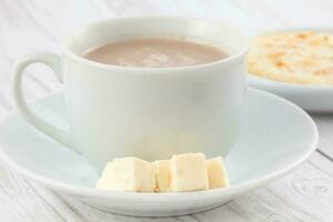 tasse de chaud Chocolat avec fromage et arepa servi dans blanc vaisselle photo