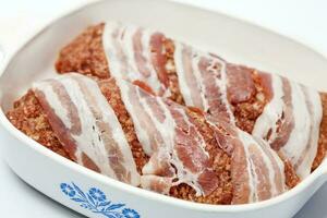 préparation de une cuit Oeuf et des légumes farci Pain de viande couvert avec bacon. Viande rouleau photo