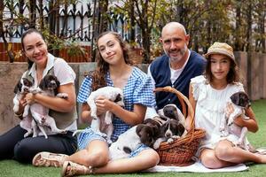 Jeune famille en plein air avec leur Nouveau née chiots dans une ensoleillé journée photo