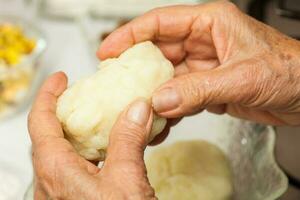 préparation pas de traditionnel colombien plat appelé farci patates. pétrissage le en purée patates par main à forme une pâte pour le farci patates photo