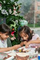 deux peu sœurs ayant amusement tandis que fabrication Noël Nativité artisanat avec à Accueil - réel famille photo