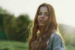 portrait de une femme avec une magnifique sourire et tout droit les dents sur une été journée dans le le coucher du soleil avec en volant frisé cheveux photo