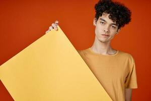 gars avec frisé cheveux Jaune affiche dans mains studio La publicité copie espace photo