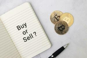 Haut vue de une pile de bitcoin avec vide carnet avec texte acheter ou vendre et à bille. crypto-monnaie commerce concept photo