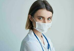 femme médecin dans une médical masque avec une stéthoscope autour sa cou photo