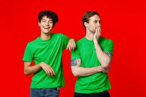 deux de bonne humeur copains dans vert t-shirts sont permanent suivant à chaque autre photo