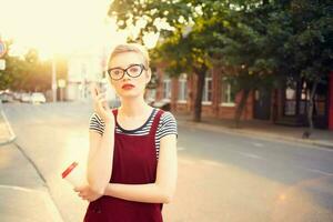 femme avec court cheveux sur le rue parlant sur le téléphone une tasse de boisson photo