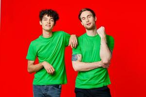 deux de bonne humeur copains dans vert t-shirts sont permanent suivant à chaque autre photo