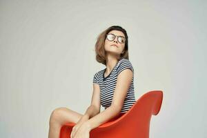 femme avec des lunettes séance sur le rouge chaise tondu vue charme photo