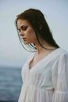 attrayant femme dans blanc robe à le mer plage liberté photo