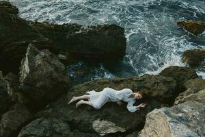 attrayant femme avec longue cheveux dans blanc mariage robe sur mer rive humide cheveux vue de au dessus photo