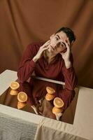 Beau homme dans une chemise à le table et une miroir avec mûr des oranges photo