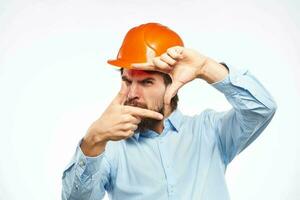 une homme dans une travail uniforme Orange difficile chapeau gestes avec le sien mains émotions construction ingénieur professionnel photo