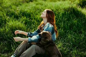 femme mensonge sur le herbe souriant en jouant et câlins sa chien dans la nature dans le parc dans le été le coucher du soleil. le concept de santé et l'amour de animaux, traitement de tiques et des puces herbe et animaux photo