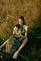 femme séance dans une champ avec une teckel chien souriant tandis que dépenses temps dans la nature avec une ami chien dans l'automne à le coucher du soleil photo