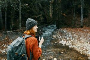 femme avec une caméra près une étang dans le montagnes sur la nature et des arbres photo