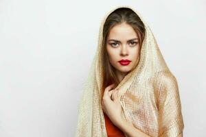 une fille dans une d'or écharpe couvertures le tête de le studio charme élégant style photo