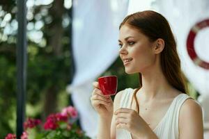 Jeune élégant femme dans une blanc robe les boissons café en plein air dans une café inchangé photo