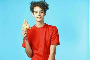 marrant frisé gars dans une rouge T-shirt Pizza livraison vite nourriture casse-croûte photo